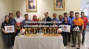 PIALA PUSINGAN: Raymond (enam kiri) menyerahkan piala pusingan kepada Jamilah sambil disaksikan Awang Putrayusrie (empat kiri), barisan exco Kejohanan Bola Sepak Liga Lundu 2018 dan wakil penaja dari Lea Sports Centre.