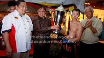 TAHNIAH: Abang Johari menyampaikan Piala Ketua Menteri Sarawak kepada Morris pada Kejohanan Muaythai Sarawak di Kuching, malam kelmarin. Turut kelihatan, Abang Abdul Wahap dan Jumaat (kiri).