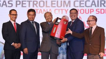 BENTUK BAHARU: Dr Mahathir (tengah) cuba mengangkat produk silinder LPG komposit, ACGAS seberat 14 kilogram selepas merasmikan produk keluaran ACG dengan kerjasama strategik dengan syarikat dari Korea Selatan, Hyundai BS&E Co. Ltd di Kuala Lumpur, semalam. Turut hadir Saifuddin (dua kiri) dan Nik Mohd Fareez (dua kanan). — Gambar Bernama