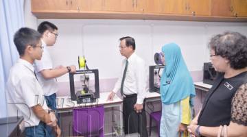 DUA pelajar memberi penerangan kepada Peter Hii serta tetamu kehormat mengenai mesin cetak 3D di Kelas Datuk Peter Hii Chang Lik SM Sung Siew.