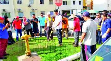 Jaffari memotong rumput sambil diperhatikan sebahagian jawatankuasa yang hadir.