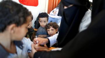 KEMPEN BERMULA: Para pelajar lain melihat seorang budak lelaki menerima vaksin demam campak dan rubella di sekolah mereka ketika program imunisasi enam hari dilancarkan di Sanaa, kelmarin. — Gambar Reuters