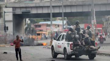 PANTAU KESELAMATAN: Dalam gambar fail ini yang diambil pada 15 Februari lalu, polis meronda di lebuh raya sewaktu protes                   antikerajaan di Port-au-Prince, Haiti. — Gambar Reuters