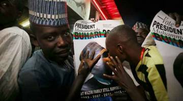 BERSUKA RIA: Salah seorang penyokong mencium poster Buhari di Kano, Nigeria selepas                                                        presiden tersebut memenangi               penggal kedua pada Selasa lepas. — Gambar Reuters