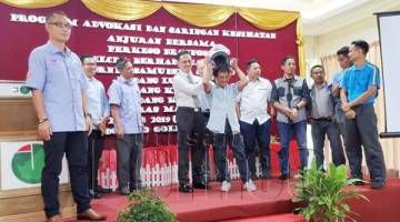 ABD. RAHMAN memakaikan helmet kepada salah seorang pekerja sempena program itu. Turut kelihatan Hj Ag Jaafar Ampuan Tuah (kiri).