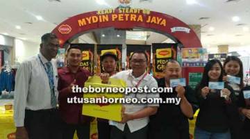 TAHNIAH: Hidayat (tengah) menunjukkan hadiah yang diterimanya semalam hasil Cabaran Maggi Pedas Giler di Mydin Tunku Vista semalam. Turut kelihatan Rethnasamy (kiri) dan peserta lain yang menerima baucar tunai Mydin.