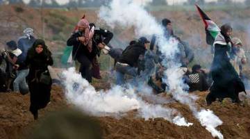 TIADA KESUDAHAN: Penunjuk perasaan Palestin lari dari gas pemedih mata yang dilepaskan oleh anggota tentera Israel sewaktu protes di pagar sempadan Israel-Gaza, selatan Semenanjung Gaza. — Gambar Reuters 