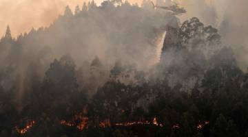 PADAM API: Sebuah helikopter menggugurkan air manakala kebakaran membara di Posada dalam wilayah Asturias di utara Sepanyol pada Selasa. — Gambar AFP