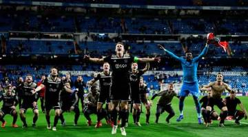 LAKAR KEJUTAN: Para pemain Ajax meraikan kejayaan mereka melangkah ke peringkat suku akhir Liga Juara-Juara bersama penyokong selepas tamat perlawanan di  Santiago Bernabeu, Madrid Selasa lepas. — Gambar AFP 
