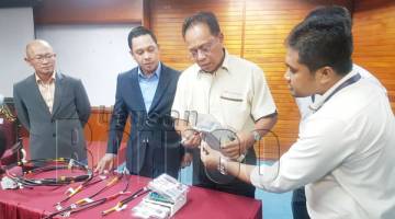 SHAFIE (tiga kiri) menunjukkan teknik usikan meter elektrik oleh pelaku sambil mempamerkan kesemua alat rampasan yang lain. Turut kelihatan Norhizami (dua kiri).