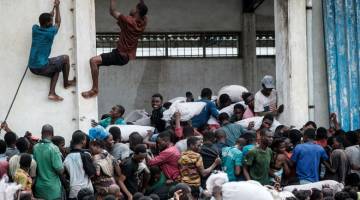 JARAH: Orang ramai menjarah guni beras dari China yang menunjukkan tanda ‘China Aid’ di Beira, Mozambique, pada Rabu, lima hari selepas siklon tropika Idai menyebabkan kemusnahan di Mozambique, Zimbabwe dan Malawi. — Gambar AFP