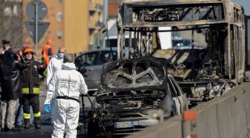 SIASAT: Anggota polis forensik dan anggota bomba bekerja di sebelah kerangka sebuah bas sekolah yang mengangkut seramai                          51 kanak-kanak dalam gambar yang diambil pada Rabu selepas ia dibakar oleh pemandu bas tersebut, di San Donato Milanese,                          ke tenggara Milan, Itali. — Gambar AFP