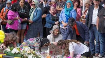 SOLIDARITI: Orang ramai termasuk beberapa wanita bukan Islam memakai tudung berhimpun untuk menyokong acara peringatan bagi mangsa serangan masjid pada minggu lepas, dalam kepungan polis untuk Pusat Islam Linwood di Christchurch, New Zealand pada Jumaat. — Gambar Reuters