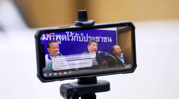 MENDAHULUI: Setiausaha Agung Parti Pheu Thai, Phumtam Wechayachai (tengah) dilihat pada skrin telefon bimbit ketika                                      beliau bercakap pada sidang media selepas partinya mendahului dalam keputusan terkini pilihan raya umum di Bangkok, Thailand pada Selasa. — Gambar Reuters