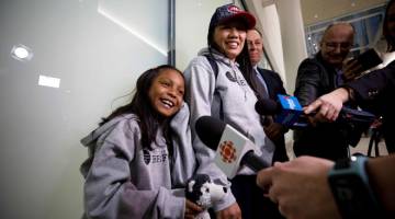 TIBA: Rodel dan anaknya Keana ditemu bual oleh wartawan di lapangan terbang Toronto, Kanada selepas mereka tiba dalam penerbangan dari Hong Kong pada Isnin. — Gambar AFP