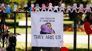 SOLIDARITI: Gambar fail 19 Mac lepas menunjukkan poster digantung di tapak peringatan untuk mangsa terbunuh dalam serangan pengganas di dua masjid di hadapan Taman Botani Christchurch, New Zealand. — Gambar Reuters