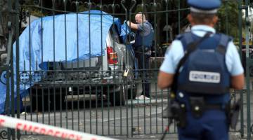 SIASAT: Anggota polis menyiasat sebuah kenderaan di tempat di mana seorang lelaki mati kerana luka tikaman di Christchurch, New Zealand pada Rabu. — Gambar AFP