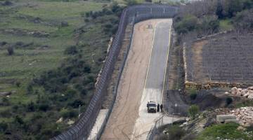 RONDA: Gambar yang diambil pada Rabu dari perkampungan Majdal Shams dalam wilayah yang dirampas oleh Israel, Golan Heights, menunjukkan kenderaan tentera Israel meronda di sepanjang pagar sempadan bersama Syria. — Gambar AFP