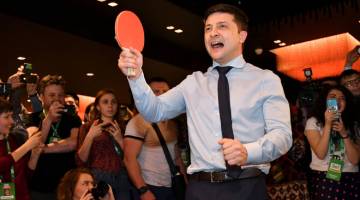 MENDAHULUI: Zelensky dikerumuni jurugambar dan jurukamera ketika bermain ping pong dengan seorang wartawan menjelang pengumuman keputusan wilayah di ibu pejabat partinya di Kiev, kelmarin. — Gambar AFP