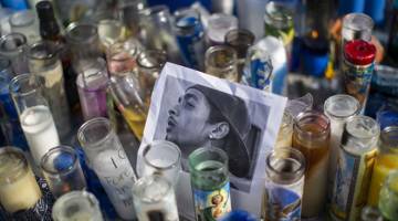 DITEMBAK MATI: Gambar Hussle dilihat di tengah-tengah lilin ketika orang ramai berhimpun untuk meratapi kematiannya                    di Los Angeles, California pada Isnin. — Gambar AFP