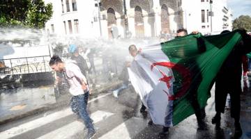 AKIBAT TIDAK PUAS HATI: Polis rusuhan menyembur penunjuk perasaan yang membawa bendera Algeria dengan air semasa                         perhimpunan antikerajaan di Algiers pada Selasa. — Gambar AFP