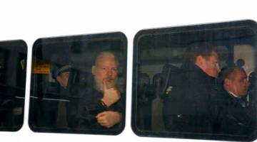 BERDEPAN PERTUDUHAN JENAYAH: Assange kelihatan menunjukkan ibu jarinya ketika dibawa dalam van polis, selepas dia ditangkap oleh polis Britain, di London pada Khamis. — Gambar Reuters