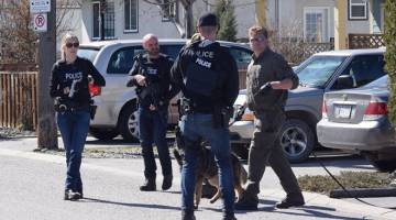 SEGERA BERTINDAK: Pegawai polis bersenjata mencari seorang suspek di Haynes Street, sewaktu siri serangan di mana empat orang ditembak mati, di Penticton, British Columbia pada Isnin. — Gambar Reuters