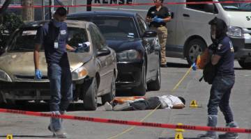 SIASAT: Pakar forensik menjalankan tugas di mana mayat seorang lelaki ditemui terbaring di atas jalan raya di Ciudad Juarez, Mexico pada Sabtu lalu. — Gambar AFP