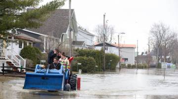 BANJIR: Penduduk menaiki traktor ketika mengharungi banjir di kawasan kejiranan Rigaud, Quebec, Kanada kelmarin. — Gambar Reuters