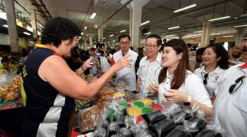 Lim (kiri) dan Wong (kanan) beramah mesra bersama peniaga ketika mengadakan lawatan mesra di Pasar Umum Sandakan hari ini. - Gambar Bernama 
