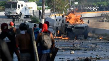 HURU-HARA: Penunjuk perasaan antikerajaan bertempur dengan anggota pasukan keselamatan semasa sambutan Hari Buruh di Caracas, Venezuela kelmarin. — Gambar AFP