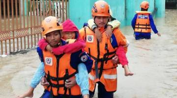 ANGGOTA APM memberikan bantuan kecemasan kepada kanak-kanak meredah banjir.