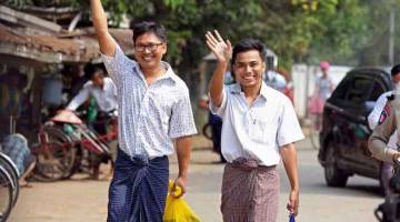 BEBAS: Wa Lone (kiri) dan Kyaw Soe Oo mengangkat tangan ketika berjalan keluar dari penjara Insein di Yangon, Myanmar semalam selepas menerima pengampunan presiden. — Gambar Reuters