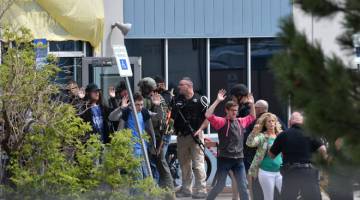 SUASANA CEMAS: Pelajar dan guru mengangkat tangan ketika berjalan keluar di bawah pengawasan pegawai polis selepas insiden tembakan di Sekolah Tinggi STEM Highlands Ranch di Colorado, Amerika Syarikat kelmarin. — Gambar AFP