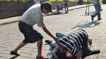 PARAH: Seorang lelaki memeluk mangsa yang cedera parah selepas penyerang melepaskan beberapa das tembakan di dataran utama di kota Cuernavaca, Morelos, Mexico kelmarin. — Gambar AFP