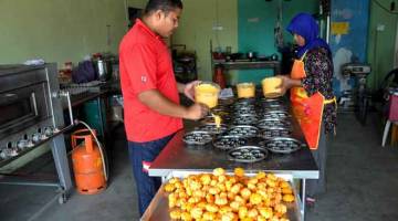 SIBUK: Fadhilah Abd Ghani (kanan) bersama adiknya Mohd Shaiful Bhari, 27, memasukkan adunan kuih nekbat ke dalam acuan sebelum dibakar bagi memenuhi permintaan orang ramai pada bulan Ramadan di bengkelnya di Kampung Pengkalan Nyireh dekat Kampung Raja, kelmarin. — Gambar Bernama