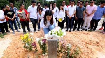 Vivian meletakkan jambangan bunga di kubur mendiang bapanya Stephen Wong Tien Fatt di Tanah Perkuburan Kristian Sandakan hari ini. - Gambar Bernama 