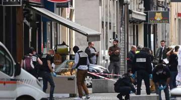 CARI BUKTI: Polis Perancis mencari bukti di hadapan premis ‘Brioche doree’ selepas letupan yang disyaki bom pakej berlaku di lebuh pejalan kaki di tengah kota Lyon, tenggara Perancis kelmarin. — Gambar AFP