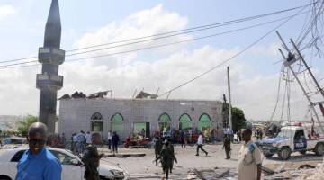 MENGGEMPARKAN: Askar dan orang ramai dilihat di tempat kejadian di Mogadishu, kelmarin. — Gambar AFP