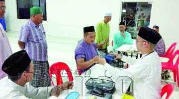 DR Wan Sherhan (kanan) metika memberikan khidmat pemeriksaan kesihatan kepada beberapa jemaah di Masjid Jamek Kg Likas.