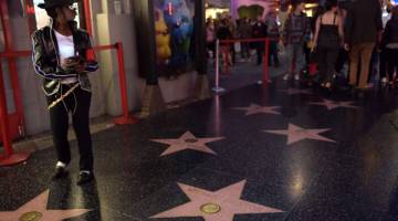 PEMINAT TEGAR: Seorang wanita berpakaian seperti Michael Jackson berdiri tidak jauh dari bintang  Hollywood Walk of Fame penyanyi itu di Hollywood pada 23 Jun lepas. — Gambar AFP
