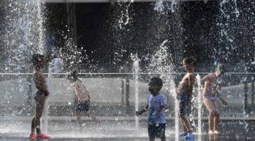 MENYEJUKKAN BADAN: Kanak-kanak bermain dalam pancutan air di dataran Aulenti di Milan, Itali ketika gelombang panas menyelubungi negara itu kelmarin. — Gambar AFP