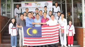 SEMOGA BERJAYA: Oscar (tiga kiri) menyampaikan bendera kepada Pengetua SMK Tiong Hin, Tan Kok Aun (tiga kanan) sambil diperhatikan Lau (empat kiri) di Sibu semalam. 