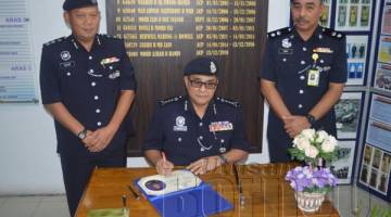 OMAR Mammah menandatangani buku lawatan IPD Sandakan sambil diperhatikan oleh Ketua Polis Daerah Sandakan ACP Mohd Azhar Hamin (kiri) dan timbalannya Supt Abdul Fuad Malek (kanan).