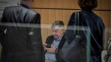 BICARA: Lombard (tengah) melihat telefon beliau di bangunan mahkamah Paris baru-baru ini ketika perbicaraan beberapa ahli pengurusan telekom gergasi atas kesalahan ‘gangguan moral’, sedekad selepas satu rentetan tindakan bunuh diri oleh pekerja. — Gambar AFP