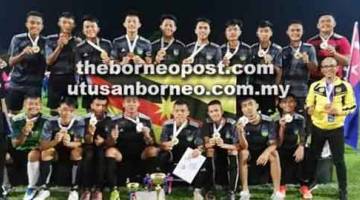 KAMI JUARA: Mohd Hakimi (kiri) bersama pasukannya mengibarkan bendera Sarawak selepas muncul juara Piala Pusingan Bola Sepak Karnival Sukan Voktek, di Johor Rabu lalu.