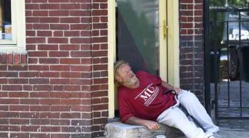 BERBAHAYA: Seorang lelaki tidur di kaki lima jalan dalam cuaca panas di Philadelphia, kelmarin. — Gambar AFP