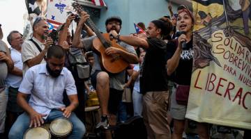 SUARA BANTAHAN: Anggota kumpulan teater Papel Machete membuat persembahan semasa menyertai bantahan untuk menuntut peletakan jawatan Rossello (kanan) di hadapan La Fortaleza di San Juan, Puerto Rico kelmarin. — Gambar Reuters