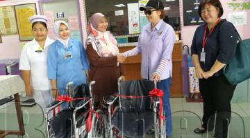 CHRISTINA (dua kanan) menyerahkan sumbangan dua kerusi roda kepada Nurul (tengah) semasa lawatan ke klinik itu.