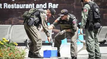 CARI PETUNJUK: Anggota unit pemusnah bom dilihat di tapak letupan bom di Bangkok, Thailand semalam. — Gambar AFP